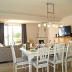 Esszimmer mit Tisch, Stühlen und Fernseher. Wohnbereich mit Sofa und Terrassentür.