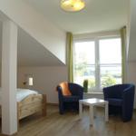 Schlafzimmer mit Doppelbett, zwei blauen Sesseln und großem Fenster mit Blick.