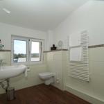 Badezimmer mit Waschbecken, WC und Heizung. Fenster mit Blick auf Landschaft.