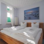 Schlafzimmer mit Bett, Nachttisch und Wandbild. Fenster mit grünen Jalousien.