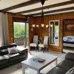 Living room with sofa, table, and view of balcony and forest.