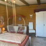 Bedroom with bed, cot, and wardrobe. Wooden walls and ceiling beams.