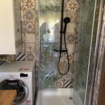 Shower cabin with glass enclosure and mosaic tiles on walls