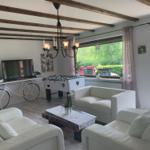 Living room with white sofas, foosball table, and bicycle against the wall.