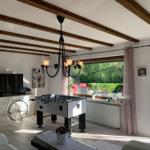 Living room with foosball table, TV, and bicycle. Doorway to terrace with garden view.