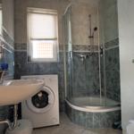 Badezimmer mit Dusche, Waschmaschine und Waschbecken