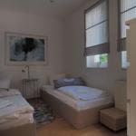 Zwei Betten, Fenster mit Jalousien, Wandbild, Nachttisch und Teppich.