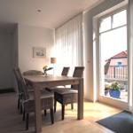 Esszimmer mit Tisch, Stühlen und Blick auf Balkon.