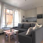 Wohnzimmer mit Sofa, Couchtisch und Küchenbereich. Fenster mit Blick auf Balkon.