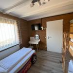 Room with bunk bed, child bed, desk, and TV mounted on the wall.