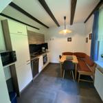 Kitchen with dining area, wooden bench, table and chairs under beams.