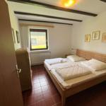 Bedroom with double bed, window, and wooden beams on the ceiling.