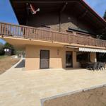 House with terrace, balcony, and garden area under blue sky.