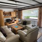 Living room with leather sofa, wooden furniture, and large windows.