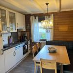 Kitchen with dining area, wooden wall, dining table and chairs, ceiling beams and pendant light.