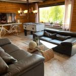 Living room with leather sofa, foosball table, and TV on wood wall.
