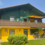 Two-story house with balcony and garden. Ground floor yellow, upper floor green.