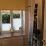 Badezimmer mit Fenster, Heizkörper und Duschvorhang.