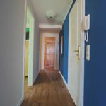 Flur mit Holzboden, blauer Wand und weißen Türen. An der Wand hängt ein Telefon.
