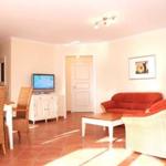 Wohn- und Essbereich mit rotem Sofa, Esstisch und Fernseher.