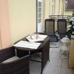 Terrasse mit Tisch, Stühlen und Gartenmöbeln. Weiße Laterne und Blumen dekorieren den Außenbereich.