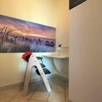 Kinderzimmer mit Hochstuhl, Schreibtisch und Strandbild an der Wand.