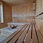 Sauna mit Holzbänken und Fenster. Thermometer an der Wand.