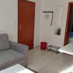 Wohnzimmer mit Sofa, Tisch und Blick in Schlafzimmer.