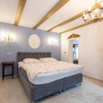 Schlafzimmer mit Bett, Schrank und Kronleuchter. Holzbalken an der Decke.