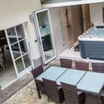 Terrasse mit Sitzgruppe, Whirlpool und Blick in das Badezimmer.