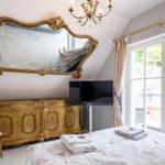 Schlafzimmer mit goldenem Schrank, Spiegel und TV. Fenster mit Blick auf Balkon.