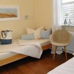 Zimmer mit zwei Betten, Sessel und Fenster mit Blick auf Dach