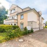 Ein zweistöckiges Haus mit gepflastertem Weg und grüner Umgebung.
