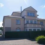 Ein zweistöckiges Haus mit Balkon und gepflegtem Garten. Hinterhof mit Zufahrt.