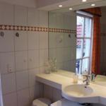 Badezimmer mit Waschbecken, Spiegel und Fenster. Fliesenwand mit dekorativer Bordüre.