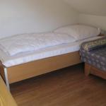 Ein Schlafzimmer mit einem Bett und einem Sofa. Holzfußboden und schräge Decke.