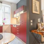 Küche mit roten Schränken und Essbereich. Wohnzimmer mit antikem Schrank und Holztisch.