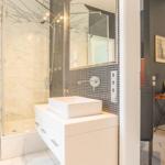 Badezimmer mit Dusche, Waschtisch und angrenzender Schlafzimmer-Ecke.