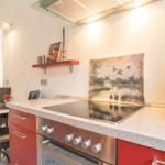 Küche mit roten Schränken, Kochfeld und Messerblock.