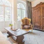 Wohnzimmer mit Sofa, Stuhl, Couchtisch und Schrank. Fenster mit Vorhängen.