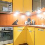 Küche mit gelben Schränken, Edelstahlherd und Mikrowelle.