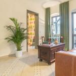 Wohnzimmer mit Ledersofa, Holzmöbel und Pflanze. Durchgang zu einem anderen Raum.