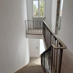 Staircase with wrought iron railing and window on upper floor