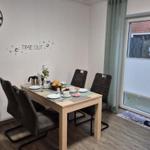 Esszimmer mit Tisch, Stühlen und Fenster. Wanduhr und Dekoration sichtbar.