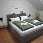 Schlafzimmer mit Doppelbett, grünen Kissen und Wanddekoration.