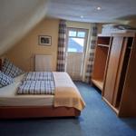 Schlafzimmer mit Dachschräge, Bett, Kleiderschrank und Fenster.