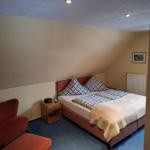 Schlafzimmer mit Doppelbett, rotem Sessel und Holznachttisch.