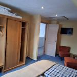 Zimmer mit Schlafbereich, Kleiderschrank und Sitzgelegenheit