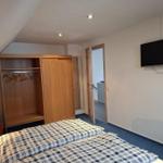 Schlafzimmer mit Bett, Kleiderschrank und Wandfernseher.