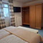 Schlafzimmer mit Doppelbett, Kleiderschrank und Fernseher.